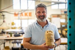 FUSE Member Pooya Rezai holding a bag containing a NooshJar and coins that he 3D printed at FUSE.